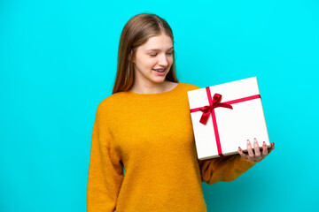 Teenager Russian girl holding a gift isolated on blue background with happy expression