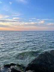 Summer sunrise, blue with orange sky, clouds and blue sea and stones