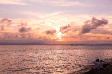 Pink sunset sky with many beautiful clouds over sea