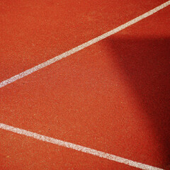 lines and shadows on a red tennis court