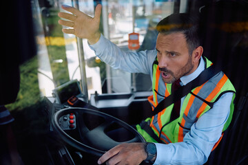 Frustrated bus driver yelling at someone while driving.