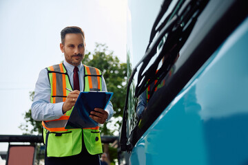 Bus driver examining bus at station. © Drazen