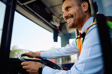 Happy driver driving public bus through city. © Drazen