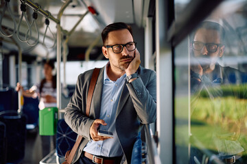 Distraught entrepreneur looking through window while riding in  bus.