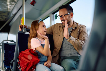 Happy father and daughter giving high-five while riding in public transport.