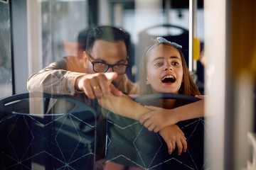 Excited girl and her father sightseeing while riding in public transport.
