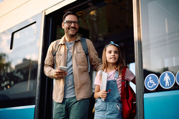 Happy father and daughter getting of  bus at  station.