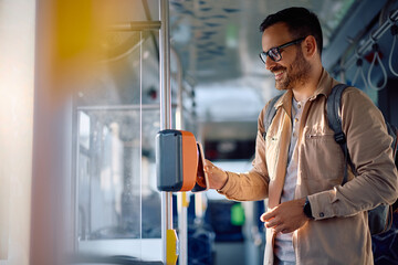 Happy man using mobile phone while paying for bus fare.