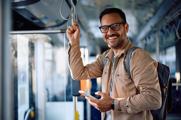 Happy man texting on mobile phone while commuting by bus and looking at camera.