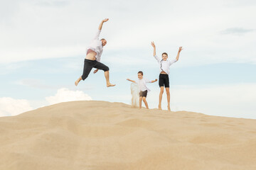 Joyful Family Leaping on Sandy Dune: Father and Sons Embracing Freedom and Adventure During Beach Vacation