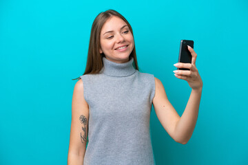 Fototapeta premium Young Lithuanian woman isolated on blue background making a selfie