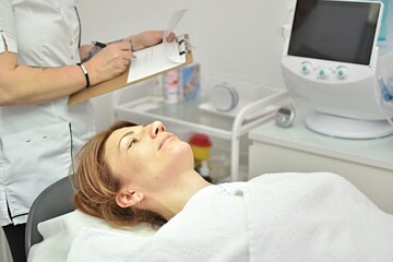 a cosmetologist writes down the data of a patient lying on the couch