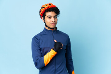 Venezuelan cyclist man isolated on blue background proud and self-satisfied
