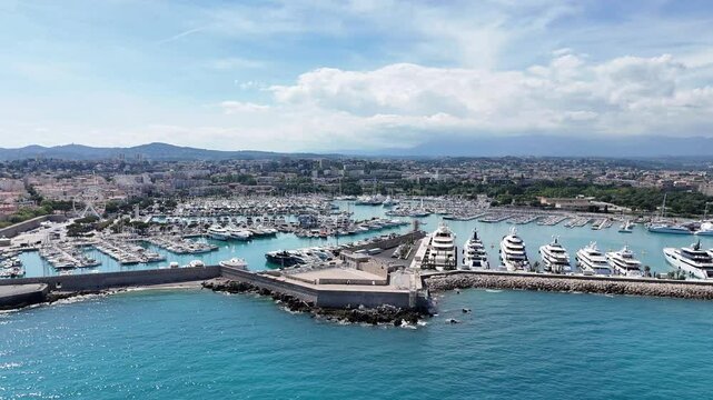 Drone shot of Antibes, France, featuring the beach, marina with boats, and the stunning C&ocirc;te d'Azur coastline along the Mediterranean Sea.