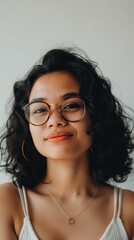 A woman with curly black hair smiles and looks at the camera