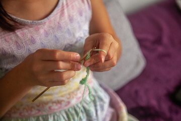 Process of crochet. Top view of young girl knitting thread, handmade for crochet, hobby for relax time in house. Selective focus on fingers. Horizontal image.