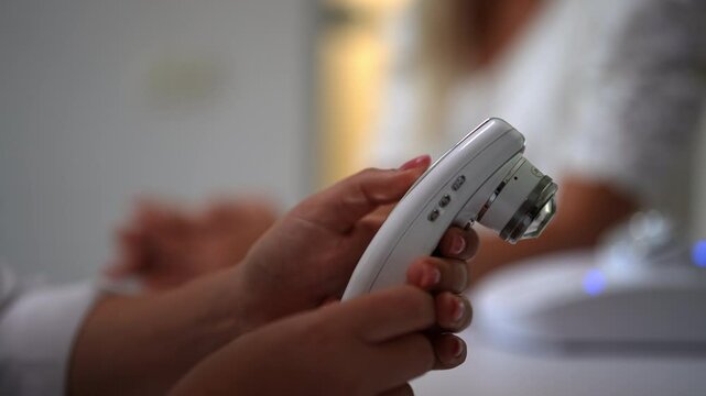 Close-up hands of unrecognizable cosmetologist dermatologist adjusting special device trichoscope in dermatological clinic. Diagnostic complex for microscopic examination of hair and skin of scalp.