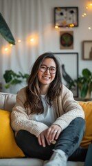 Fototapeta premium A woman with long dark hair sits on a couch and smiles at the camera