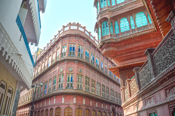 Dulmera Havelis in Bikaner with windows in green tones and touristy red facades