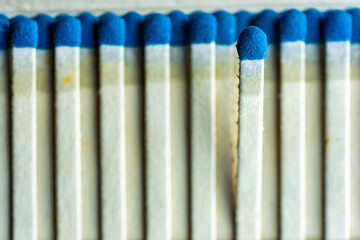 A blue match head focused on a blurred background of blue cardboard matches.