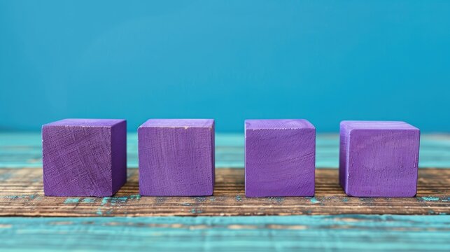 Four purple wooden blocks arranged in a line on sturdy oak surface with space for text against blue backdrop