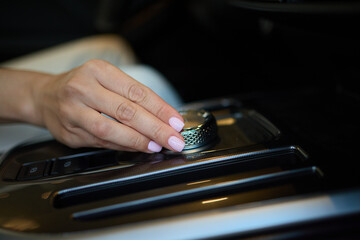 A woman adjusts a control knob in a modern car to enhance comfort while driving