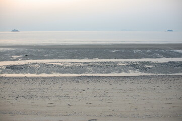 a beach with a hill in the background and a person in the water