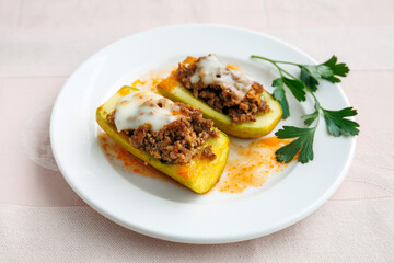 Zucchini stuffed with minced meat, vegetables and cheese. Zucchini boats. Turkish name kabak sandal. On white plate close up