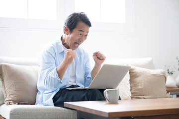 パソコンを見てガッツポーズをする男性