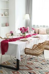 Beautiful table setting with pink accent and rattan chairs in dining room