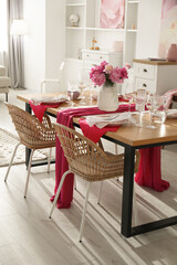 Pink peonies on table with beautiful setting and rattan chairs in dining room