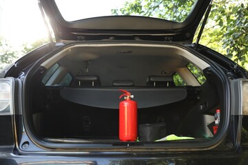 Red fire extinguisher in trunk. Car safety equipment