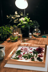 Table, frame and pressing flowers for creative hobby with decor, florist service and startup in...