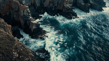 aerial oberhead drone shot from above of coastal cliffs with waves crashing against the rocks, powerful and dynamic natural scene. wallpaper background for ads, web design, sites and frames. 16:9