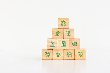 .A pyramid of wooden blocks, each featuring a green eco-friendly icon, stands against a white background.