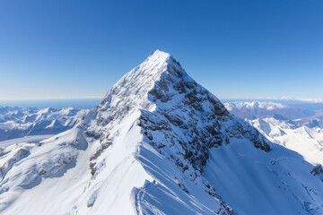 A mountain peak covered in snow with a blue sky in the background