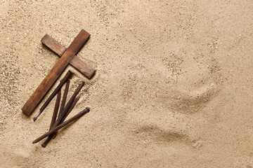 Wooden cross with nails on sand. Good Friday concept