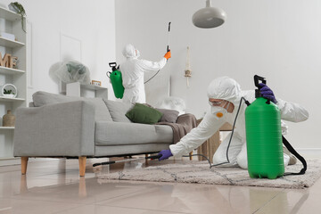 Male workers in hazmat suits disinfecting room