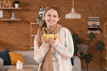 Happy young woman with sore throat and cup of tea at home
