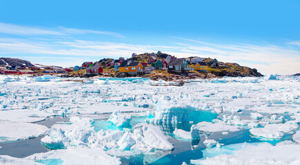 Panoramic view of colorful Kulusuk village in East Greenland - Kulusuk, Greenland - Melting of a iceberg and pouring water into the sea © muratart