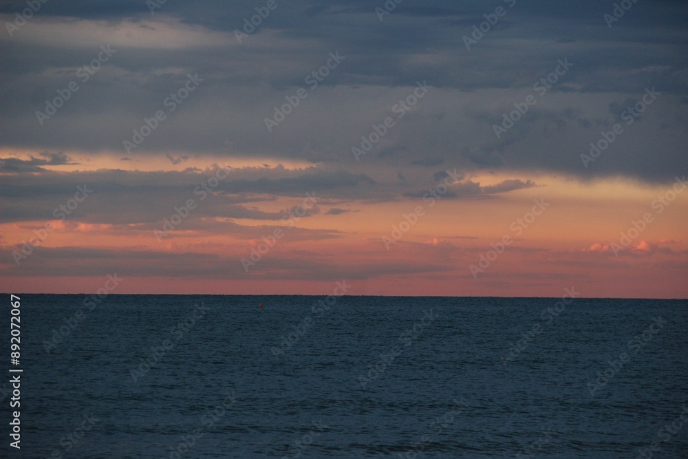 Sticker Serene ocean view at sunset with a dramatic sky and calm waters