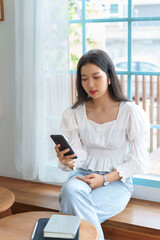 Obraz premium Young asian businesswoman talking and meeting with colleague in video conference on smartphone after analysis strategy about investment and planning of new startup project while working in cafe