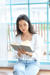 Young asian businesswoman enjoying to reading literature the book and relaxation with drinking coffee after analysis strategy about investment and planning of new startup project to working in cafe