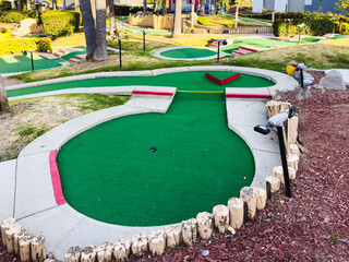 Mini-golf course with multiple holes and obstacles surrounded by greenery.