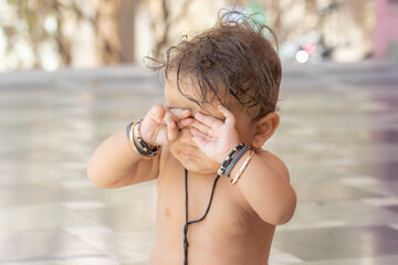 Adorable Indian Baby Rubbing Eyes Outdoors in a Sunny Day