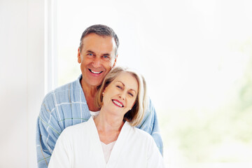 Portrait, love and window with senior couple, hug and support in living room of house together. Smile, face and trust with happy, mature man and woman bonding while enjoying retirement at home