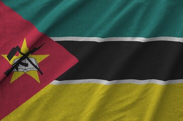 Mozambique flag depicted on folded wavy fabric of old cloth close up