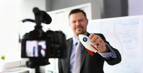 Businessman hold rocket in hand closeup on office background business concept