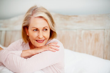 Naklejka premium Mature woman, thinking and relax on bed in hotel on holiday for retirement, leisure and wellness. Female person, idea and comfort in bedroom at lodge while on vacation for peace, health and break
