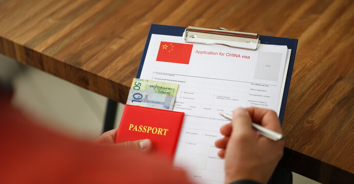 Male hand hold silver pen with passport. Filling China apllication form concept